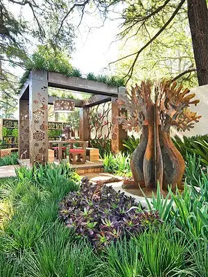 Prefabricated outdoor pavilion with decorative corten steel panels and sculptural tree artwork at Melbourne show garden