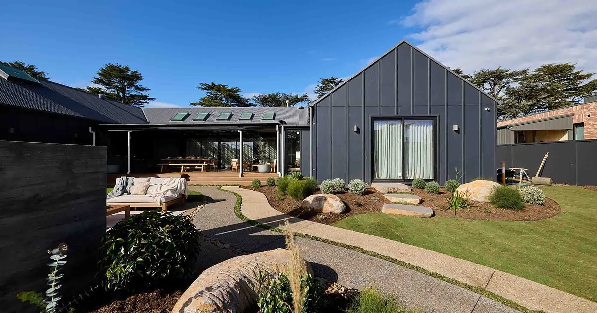 Modern landscape courtyard with basalt stepping stones, outdoor daybed, and steel-clad buildings at Daylesford House 5