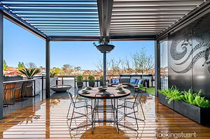 Modern rooftop terrace with blackbutt timber decking, round dining table, wire chairs and pergola overlooking St Kilda