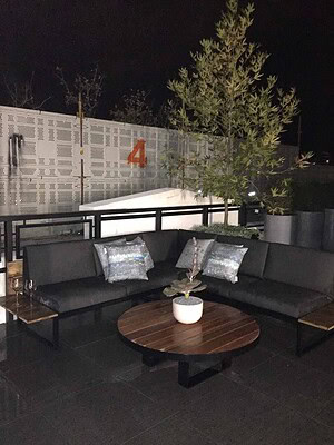 Blackbutt timber dining deck with round table and dark lounge seating on St Kilda rooftop terrace at night