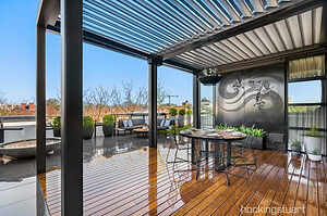 Modern rooftop terrace with steel pergola, blackbutt decking, dining table and city views in St Kilda