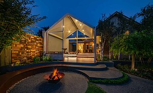 Modern pavilion with glass roof and curved corten seating around fire pit at twilight in Ballarat backyard