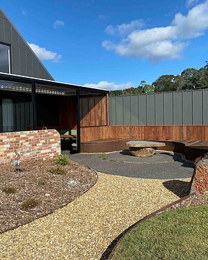 Curved exposed aggregate paths connecting timber deck to pool area with bluestone steps in Gisborne Macedon Ranges garden