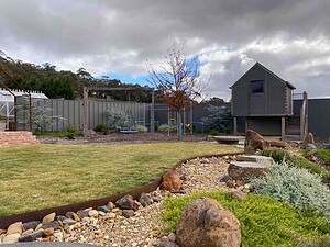 Curved exposed aggregate paths connecting deck to pool area in Gisborne country garden with native plantings and lawn