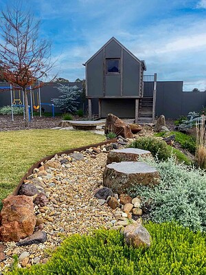 Dry stone creek bed with stepping stones and native plantings in Gisborne Macedon Ranges garden with cubby house