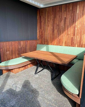 Built-in timber dining booth with mint green upholstery and terrazzo flooring in Gisborne project